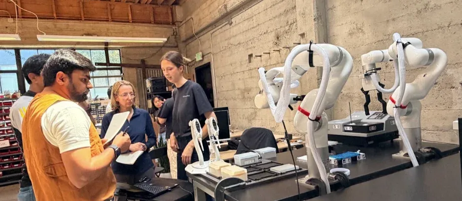 Builders working with robotic arms on the closed-loop biology track